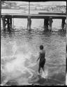 Boy diving for pennies, with a bridge in the background