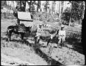 Two men standing with a donkey and a mule in front of a small building