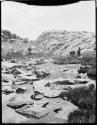 Man standing with a donkey and a mule on rocky terrain