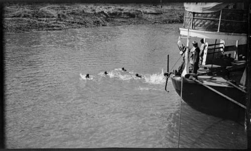 People swimming in front of an Irrawaddy Flotilla Company boat