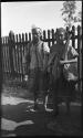 Two people standing in front of a fence