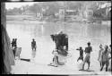 People standing in the water next to an elephant