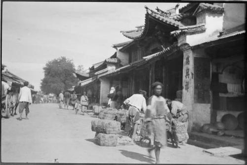 People working with bundles and walking in front of a building