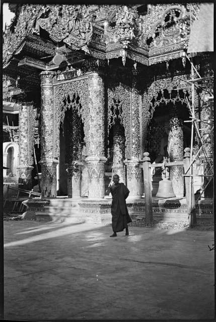 Person standing next to a bell in front of a temple