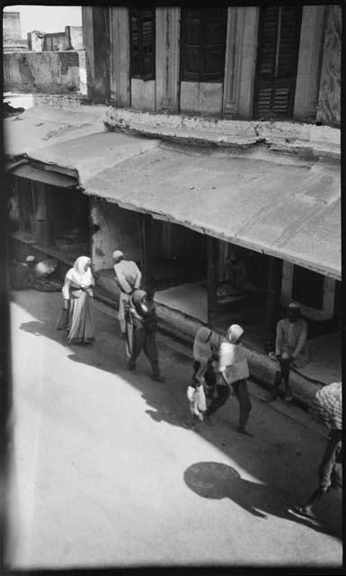 People walking down a street in front of a building