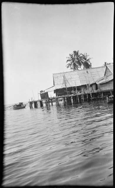 People on a boat next to buildings on stilts