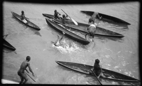 Person diving into the water from a boat, surrounded by people in boats