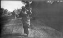 Person carrying a basket, walking down a road