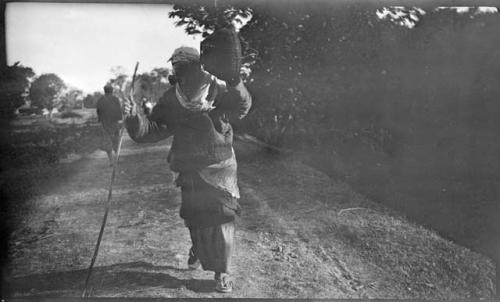 Person carrying a basket, walking down a road