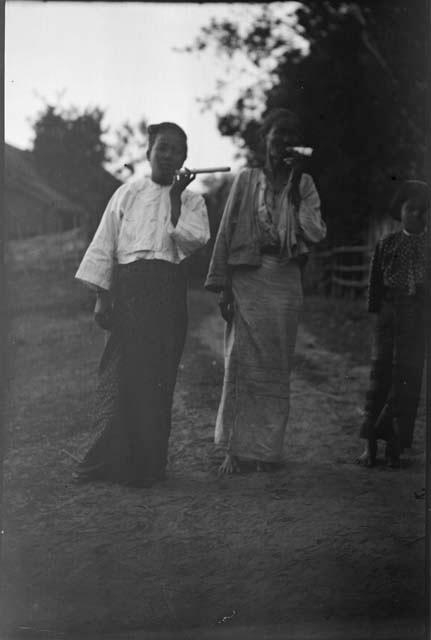 Two people smoking, with another person standing next to them