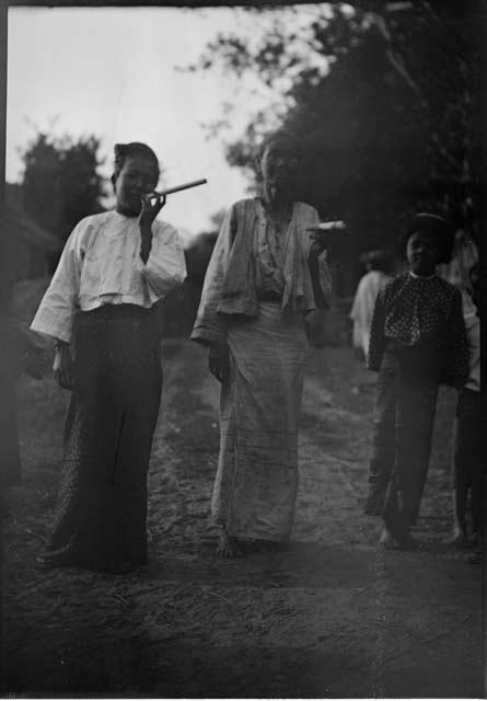 Two people smoking, with another person standing next to them