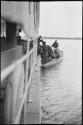 People on a small boat next to a larger boat