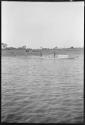 Two people with a boat, with people standing behind them on shore