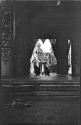 Two monks squatting in the doorway of a temple