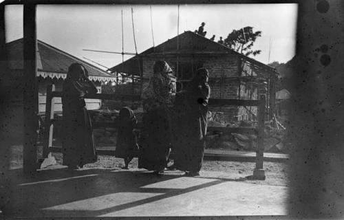 People standing in front of a fence, with a building in the background