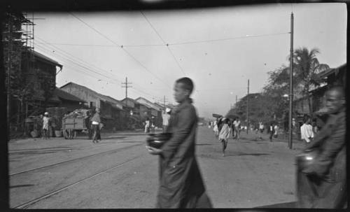 Monks carrying containers across a street