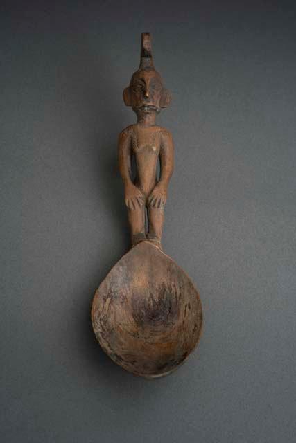 Wooden spoon, handle carved in human effigy: hands resting on flexed knees, hair