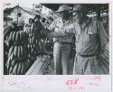 Two men looking at bananas on their right