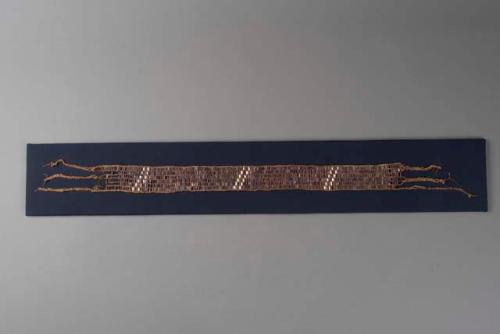 Wampum belt. Mostly purple wampum w/ 6 diagonal white stripes.