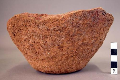 Ceramic partial bowl, plain red ware, flat base, splayed sides, flaking surface