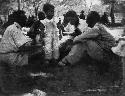 Child of Senhor Simões standing next to three men sitting in the expedition camp