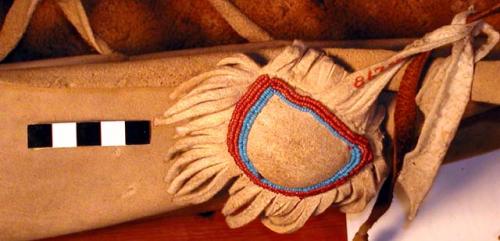 Buckskin navel string pouch filled with feathers and attached to cradleboard