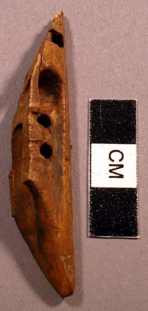 Fragment of worked bone, brown with 4 perforations