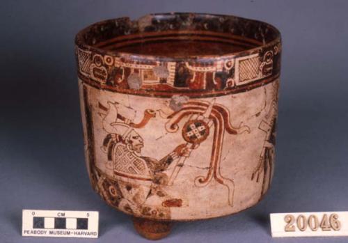 Polychrome cylindrical pottery vase with tripod feet. Seated and standing human