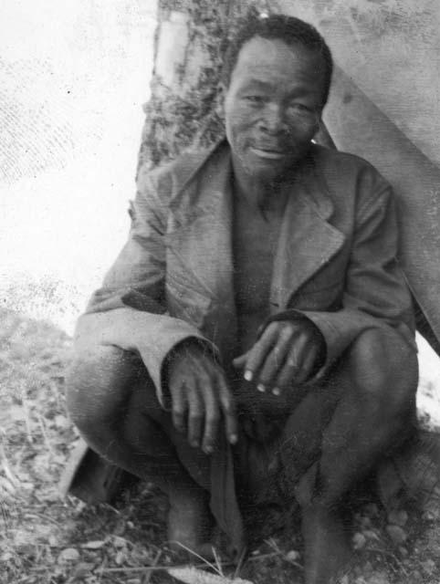 Garu (Headman) wearing a coat, sitting