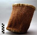 Bag of Indian hemp twine closely woven, stiff rawhide bottom, mouth edged with leather, used as a mortar bag.