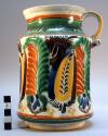 Majolica ware pitcher with stylized floral design in orange, brown, green, blue,