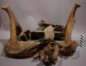 Plains saddle w/ 2 stirrups. Wood covered w/ rawhide. High cantle and mantle.