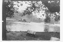 Men taking tractor up river in a canoe