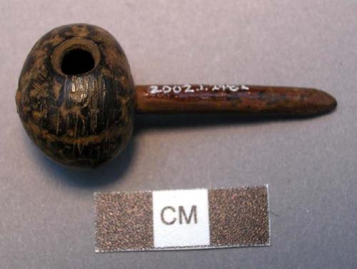 Unclassified, hollowed nut?, side perforation, at base of carved stick