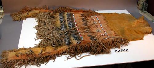 Deerskin skirt. Made of dyed leather with fringe. Decorated with metal jingles