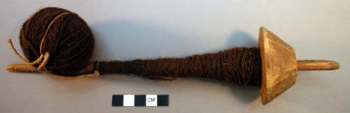 Wooden spindle wound with yarn and ball of yarn attached