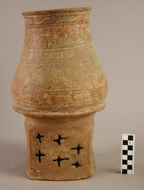 Tall raised-base pottery vessel with rattle in the base; worn painted decoration