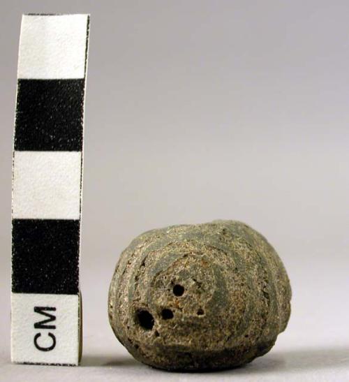 Ceramic spindle whorl, black, spherical, incised circular design, pitted surface