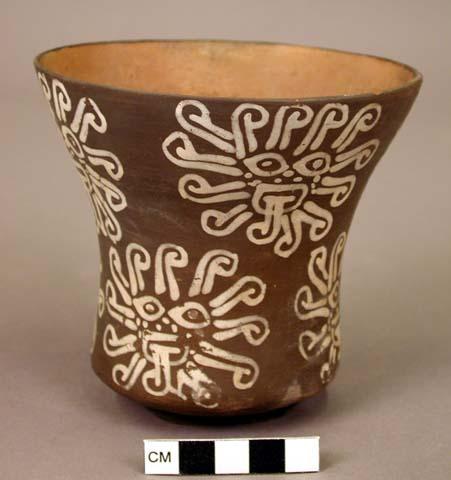 Brown goblet painted in white with nine rayed faces and one rosette