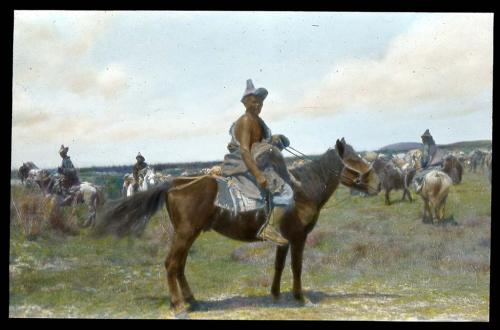 Lantern slide of man on horseback, others behind him, hand-colored