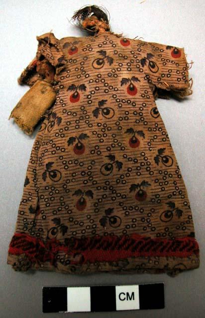 Cloth doll in long dress of printed cotton cloth with red woolen band around hem