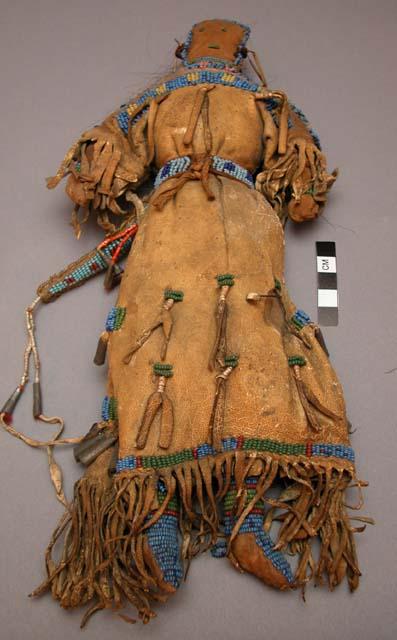 Female doll wearing leather dress w/ beadwork & fringe.