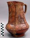 Pitcher with applied and incised decoration. Brown glazed pottery.