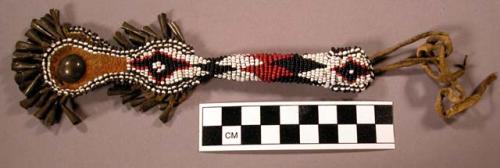 Awl case. Made of yellow buckskin. Red, white, and black beadwork.