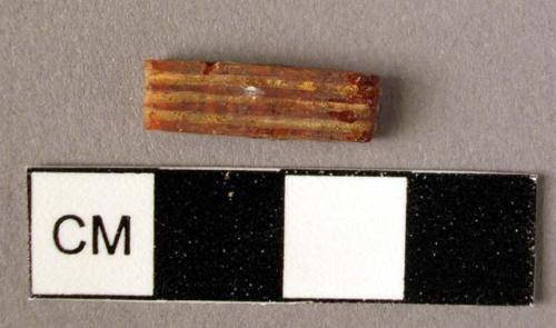 Rectangular amber spacer, decorated on one side with three grooves