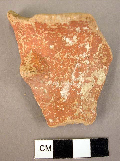 Red, lustreless, glazed pottery rim fragment with lug