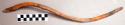 S-shaped stick with incised lines. Catalog: “miniature grooved throwing stick”.