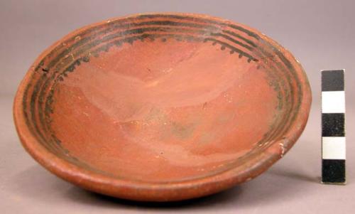 Restored shallow pottery vessel, red with black decoration