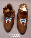 Pair of moccasins with beaded center, floral decoration of white background red