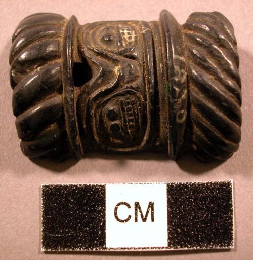 Ornament, black stone, carved both sides, anthropomorphic & geometric designs